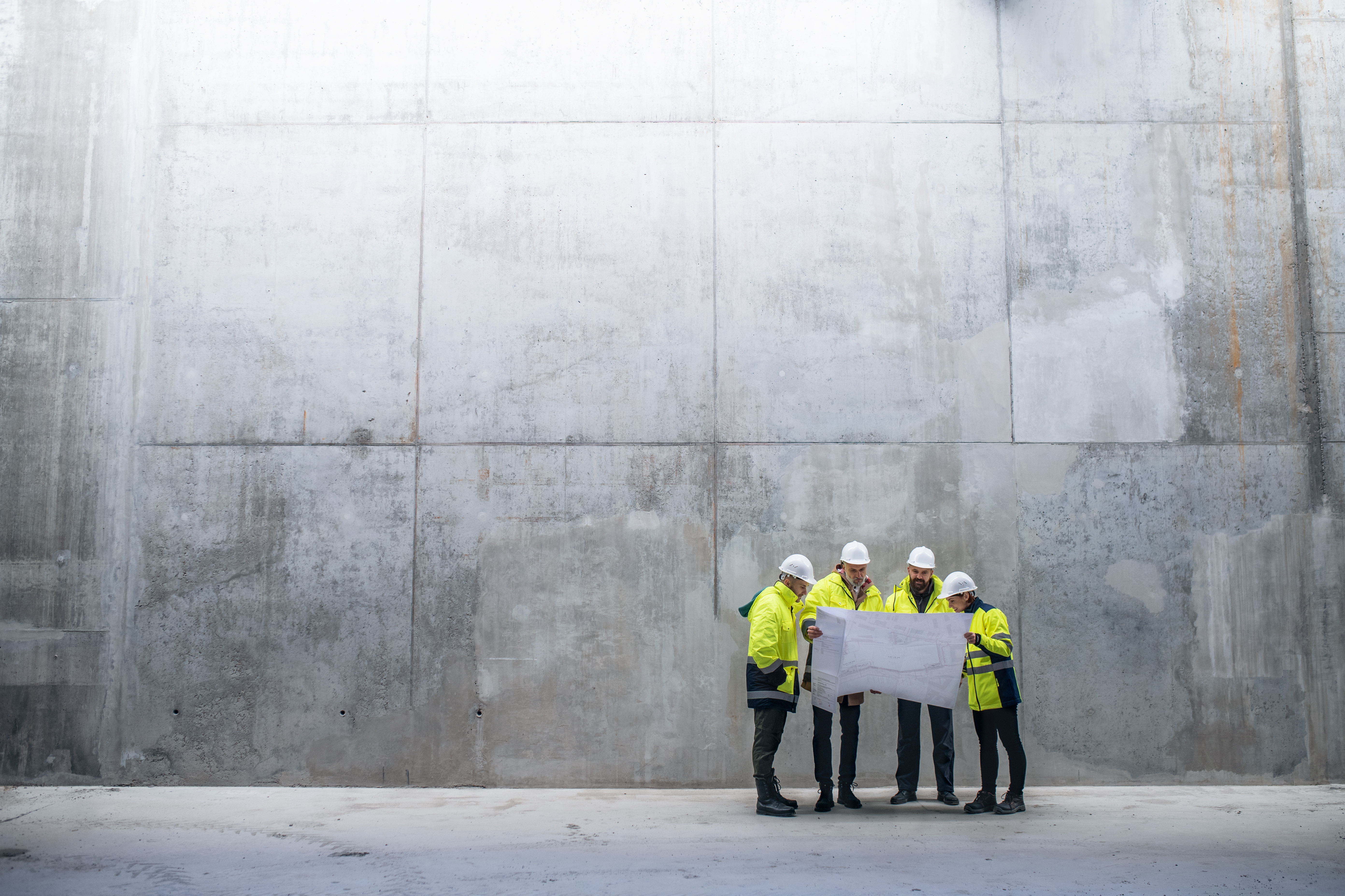 Groupe d'ouvriers regarde un plan avec bâtiment en fond